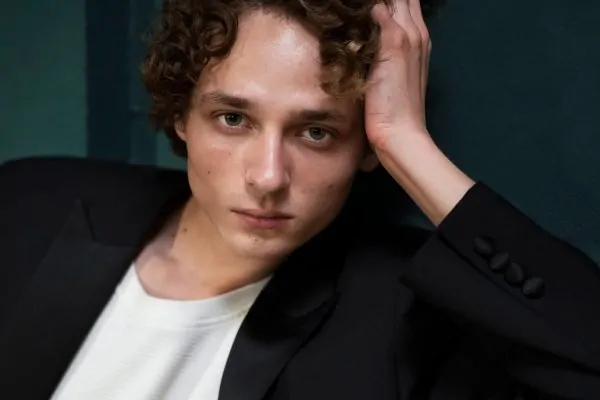 Young man with curly hair in thoughtful pose, demonstrating natural facial contours relevant to PDO thread lift treatment planning