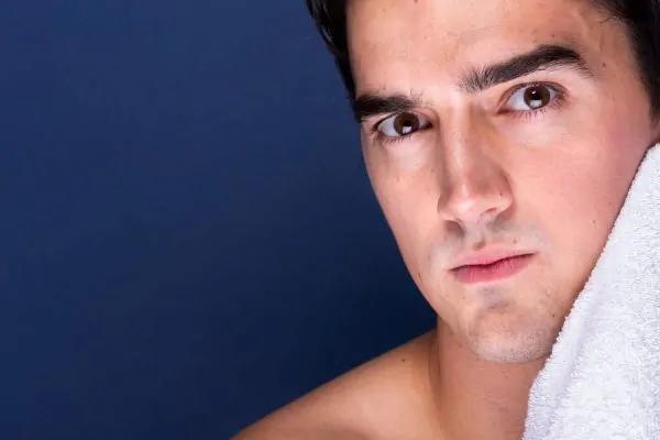 Adult male cleaning face with towel