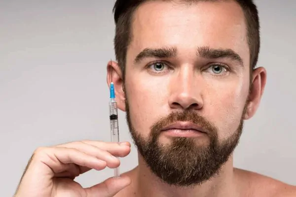 Man holding a syringe next to his face