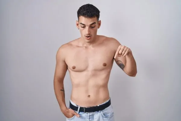 man standing shirtless pointing down