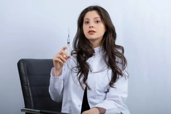 Portrait of female doctor holding a large syringe