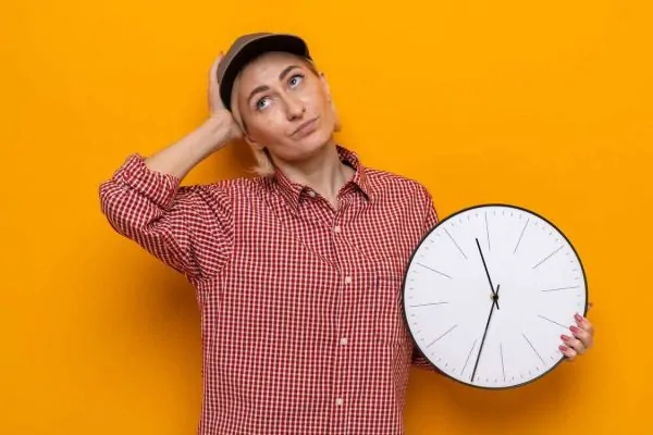 woman in plaid shirt and cap holding clock